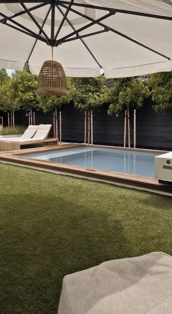 zwembad tuin met grasveld en ligbedden